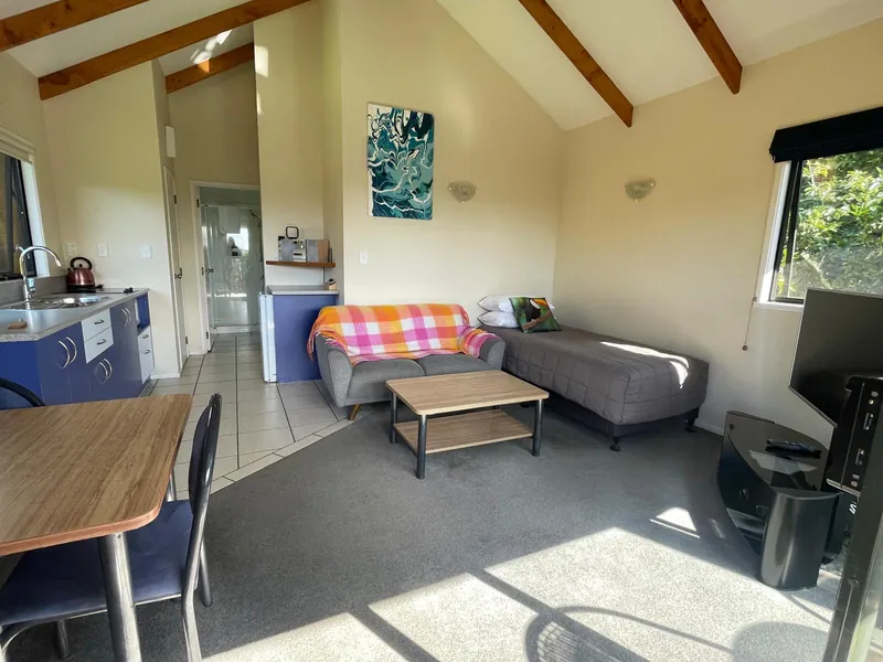 Open-plan chalet lounge with kitchen, sofa bed and orchard views, Kerigold Chalets