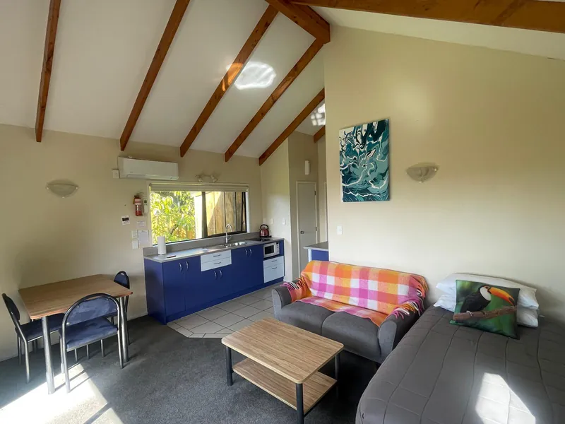 Open-plan lounge and kitchen with exposed beams, Boutique Chalet Kerikeri